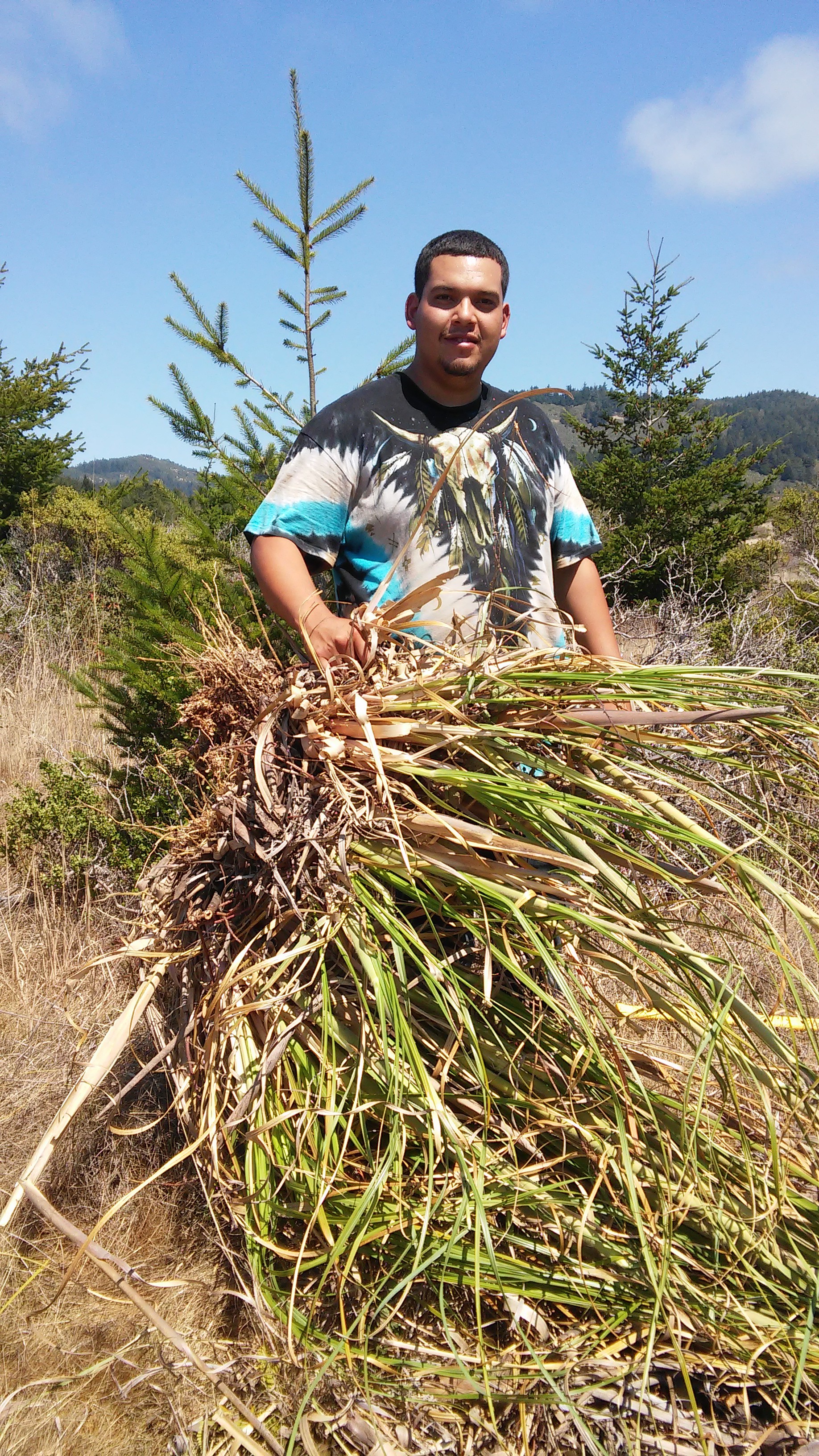 Native Steward Nathan Vasquez with the root ball of a clump of Pampas grass, recently removed from the Costanoa Easement.